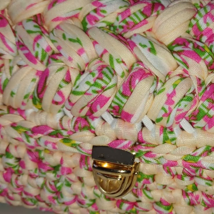 Close-up of a floral fabric-yarn crochet bag with a gold clasp